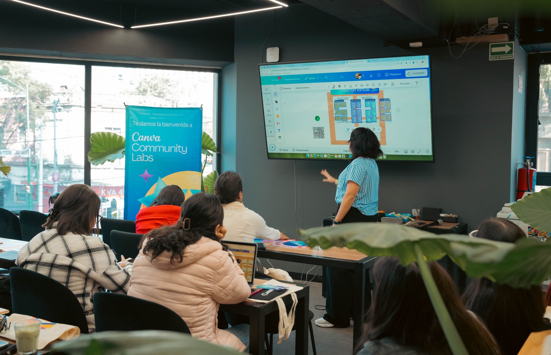 formateur utilisant un écran interactif dans une salle de formation, avec participants suivant une activité visuelle et collaborative