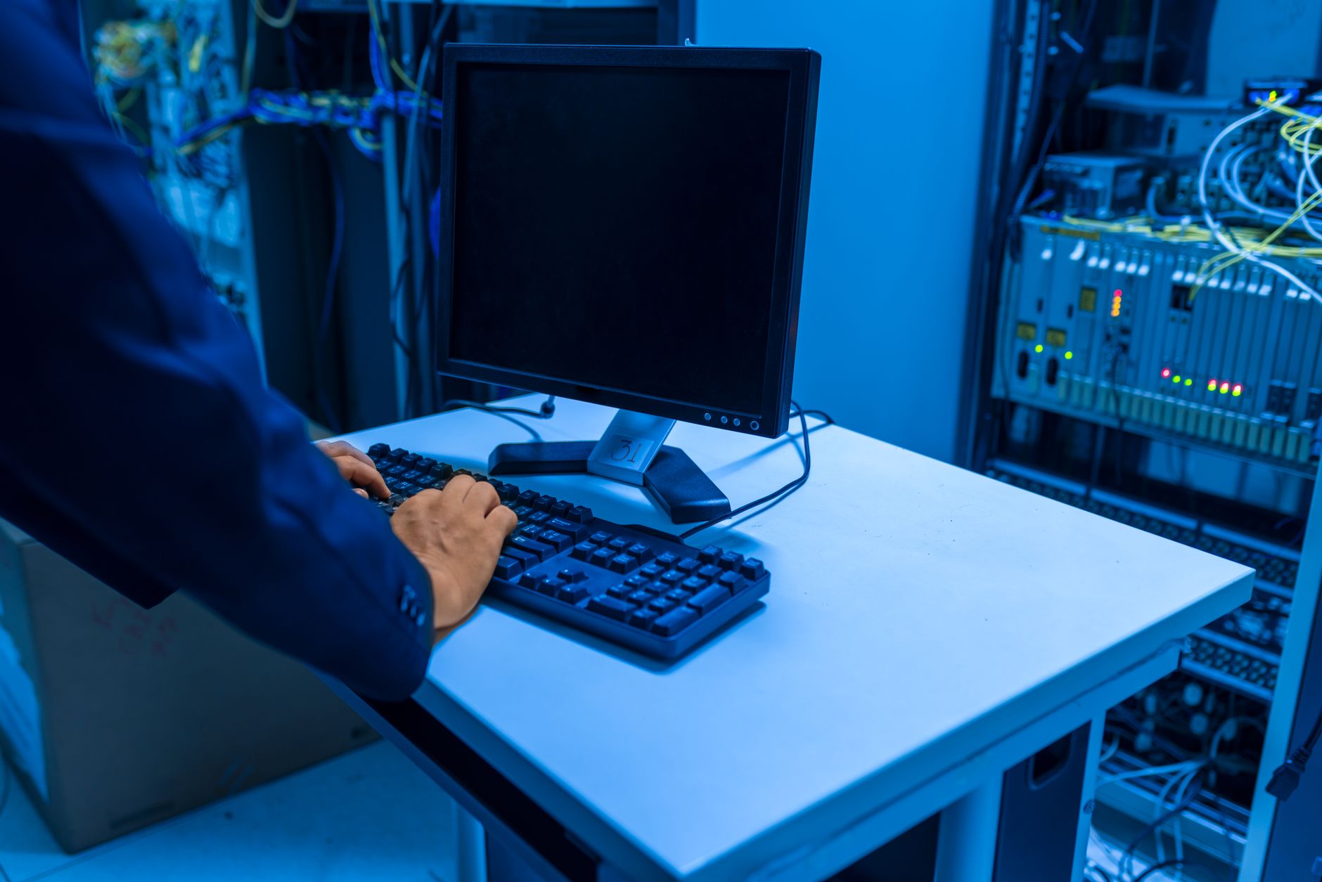 Technicien configurant un écran interactif tactile dans une salle de formation, avec câbles et ordinateur visibles de manière professionnelle